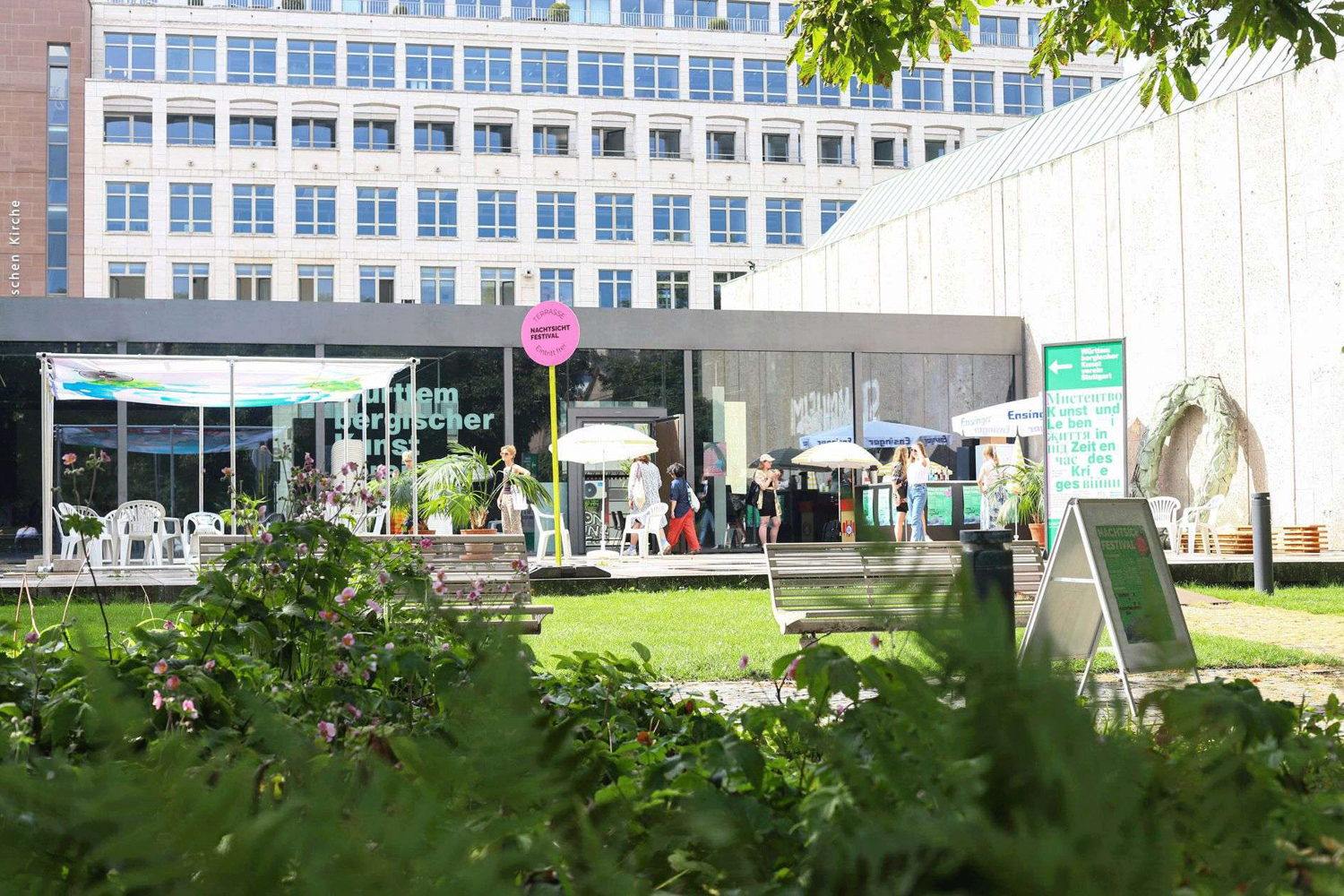 Der Württembergische Kunstverein ist von Weitem zu sehen. Menschen gehen herein und ein pinkes Schild, mit der Aufschrift "Nachtsicht Festival" steht vor dem Gebäude.